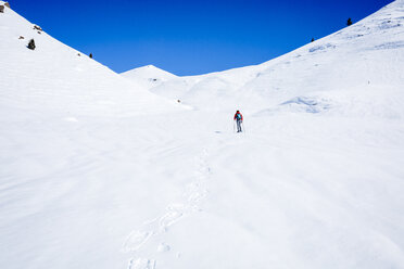 Blick aus mittlerer Entfernung auf einen Wanderer, der auf einem schneebedeckten Berg im Joshua Tree National Park wandert - CAVF15326