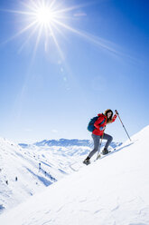 Weiblicher Wanderer beim Klettern auf einen schneebedeckten Berg gegen den Himmel an einem sonnigen Tag - CAVF15329