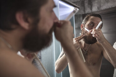 Junger Mann schaut in den Spiegel im Badezimmer, lizenzfreies