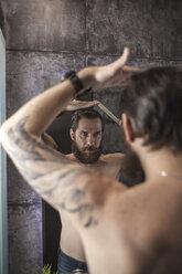 Porträt eines bärtigen Mannes, der sein Spiegelbild betrachtet, während er sein Haar kämmt - VPIF00387