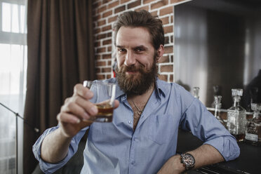 Portrait of smiling man with glass of whiskey at home - VPIF00393