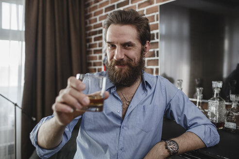 Porträt eines lächelnden Mannes mit einem Glas Whiskey zu Hause - VPIF00393