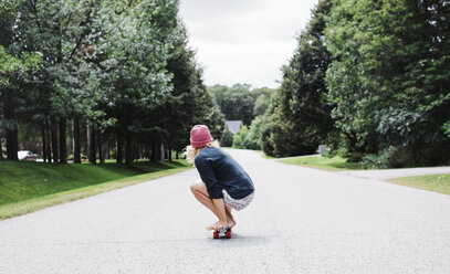 Seitenansicht einer Frau, die auf einem Skateboard hockt - CAVF15358