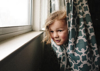 Playful girl peeking while hiding in curtain - CAVF15395