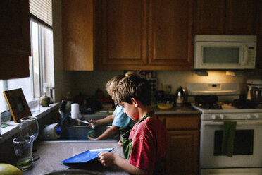 Siblings cleaning utensils in kitchen - CAVF15410