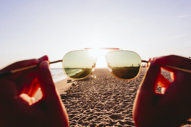 Ausgeschnittenes Bild einer Person mit Sonnenbrille am Strand im Sommer - CAVF15431