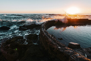 Waves splashing on retaining wall in sea during sunset - CAVF15450