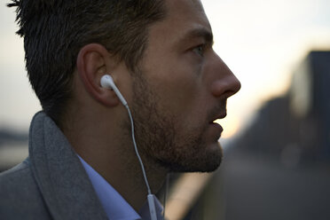 Close-up of businessman looking away while listening music - CAVF15479