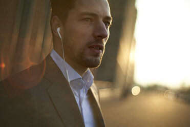 Confident businessman listening music while standing outdoors - CAVF15481