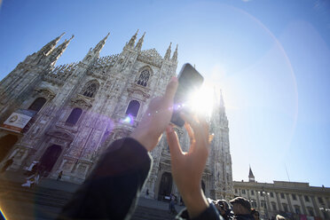 Cropped image of woman photographing Duomo Di Milano against clear blue sky - CAVF15505