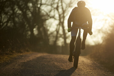 Silhouette Frau fährt Fahrrad auf Gehweg gegen Himmel während Sonnenuntergang - CAVF15517