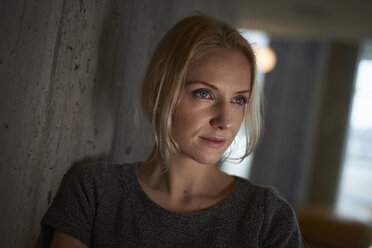 Thoughtful businesswoman looking away while leaning on wall at hotel room - CAVF15526