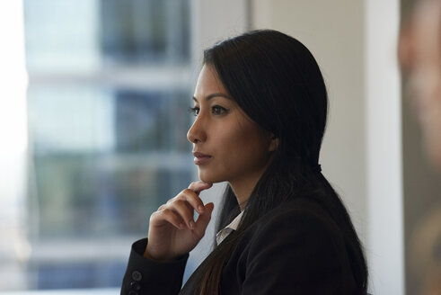 Nachdenkliche Geschäftsfrau schaut durch ein Fenster im Büro - CAVF15538