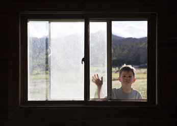 Porträt eines Jungen, der durch ein Fenster schaut - CAVF15548