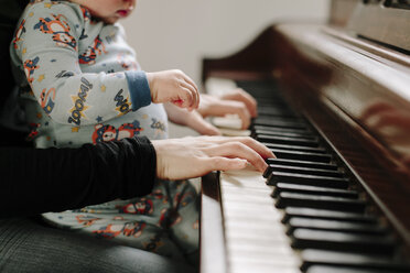 Mittelteil einer Mutter mit ihrem Sohn, der zu Hause Klavier spielt - CAVF15564