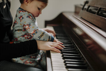 Sohn sitzt bei der Mutter und spielt zu Hause Klavier - CAVF15565