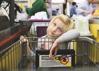 Gelangweiltes Mädchen mit Einkaufswagen im Supermarkt - CAVF15600