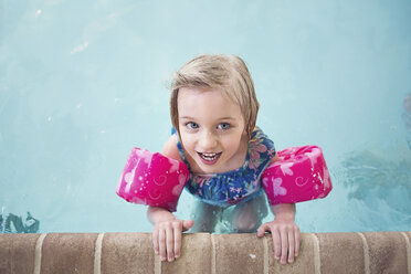 Portrait of happy girl wearing water wings swimming in pool - CAVF15602