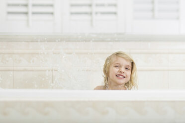Fröhliches Mädchen spritzt beim Baden in der Badewanne zu Hause mit Wasser - CAVF15604
