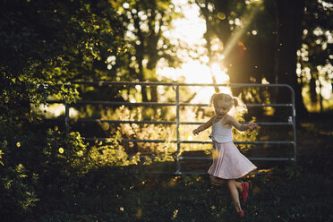 Fröhliches Mädchen tanzt auf einem grasbewachsenen Feld im Hinterhof - CAVF15610