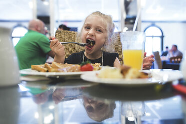 Verspieltes Mädchen beim Essen im Restaurant - CAVF15617