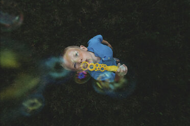 Draufsicht auf einen Jungen, der auf einer Wiese Seifenblasen bläst - CAVF15623
