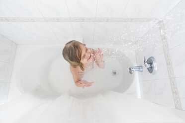 High angle view of girl with eyes closed enjoying shower in bathtub at home - CAVF15624