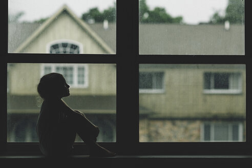 Nachdenkliches Mädchen sitzt auf der Fensterbank vor dem Haus - CAVF15627