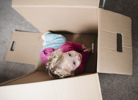 Hohe Winkel Ansicht der spielerischen Mädchen sitzen in Karton zu Hause, lizenzfreies Stockfoto