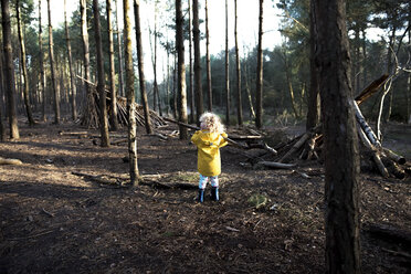 Rear view of playful girl carrying stick in forest - CAVF15670