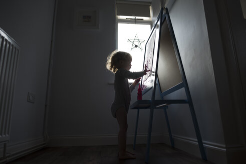 Silhouette girl painting on paper attached to whiteboard - CAVF15687