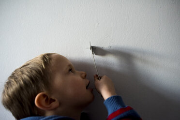 Nahaufnahme eines Jungen, der zu Hause an der Wand mit einem Spielzeug spielt - CAVF15697