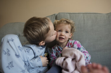 Junge küsst Schwester, während er zu Hause auf dem Sofa sitzt - CAVF15700