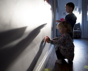 Geschwister kleben Haftnotizen an die Wand zu Hause - CAVF15703