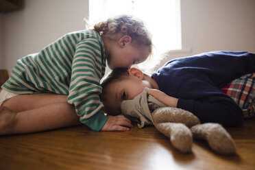 Seitenansicht eines Mädchens, das seinen Bruder zu Hause auf den Kopf küsst - CAVF15708