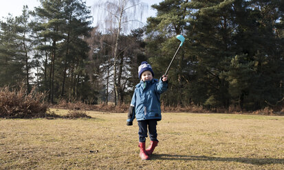 Full length boy with golf stick walking on field - CAVF15711