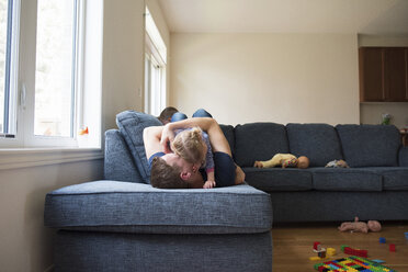 Glücklicher Vater spielt mit Kindern auf dem Sofa zu Hause - CAVF15759