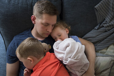 High angle view of father with children sleeping on sofa at home - CAVF15760