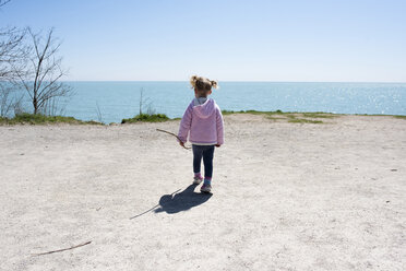 Rückansicht eines Mädchens, das auf einer Klippe am Meer spazieren geht, gegen einen klaren Himmel - CAVF15767
