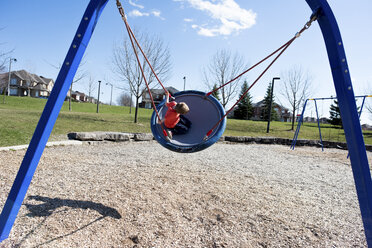 Boy playing on swing at park on sunny day - CAVF15770
