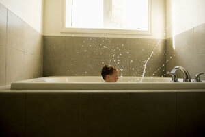 Junge spritzt Wasser beim Baden im Badezimmer - CAVF15787