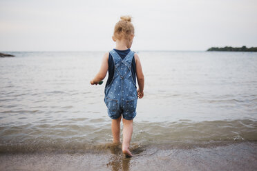 Rear view of girl walking on beach in sea against clear sky - CAVF15831