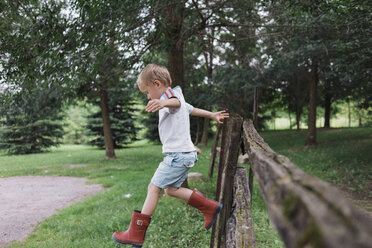 Full length of boy jumping from fence at park - CAVF15838