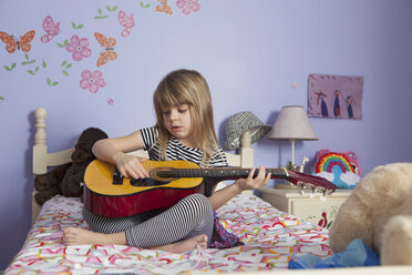Mädchen spielt Gitarre auf dem Bett zu Hause - CAVF15866