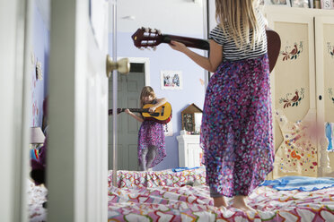 Mädchen hält Gitarre und schaut in den Spiegel, während sie auf dem Bett steht - CAVF15868