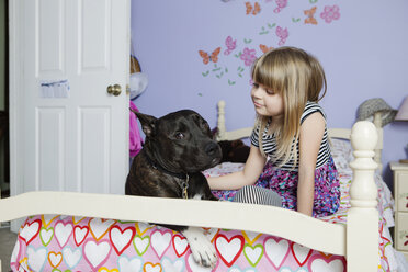 Nettes Mädchen mit Hund auf dem Bett zu Hause - CAVF15870