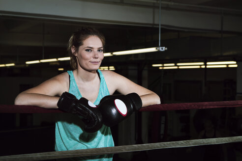 Porträt einer lächelnden Sportlerin, die in einem Boxring im Fitnessstudio steht - CAVF15877