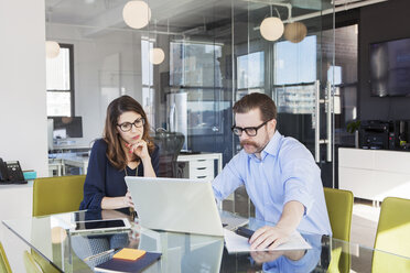 Mature business colleagues using laptop together in board room - CAVF15921