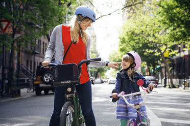Happy woman touching daughter's nose while standing with Citi Bike on street - CAVF15959