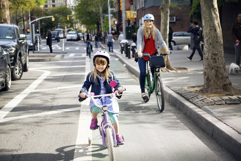 Porträt von Mutter und Tochter auf Fahrrädern auf der Straße, lizenzfreies Stockfoto
